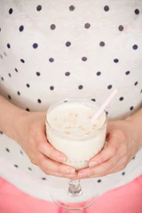 Young woman with a big glass of healthy smoothie served with a straw and oats. Hands holding milkshake. Stars background. Dairy snack or breakfast.