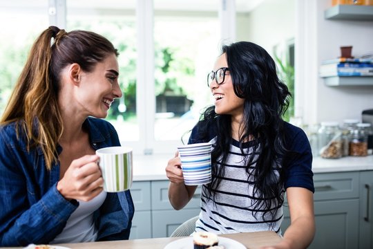 Young Female Friends Laughing While Drinking Coffee