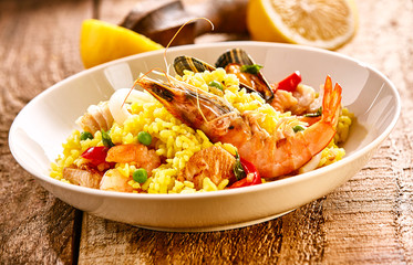 Fresh Seafood Paella Dish with Lemon on Wood Table