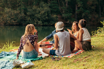 Young people having picnic near a lake