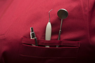 dettaglio di vari strumenti per dentista posti nella tasca di un camice 