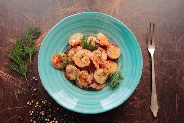 Fresh shrimps served on a blue plate with dill
