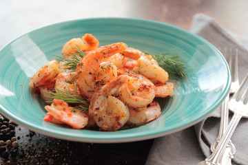 Grilled shrimps with dill on a blue plate