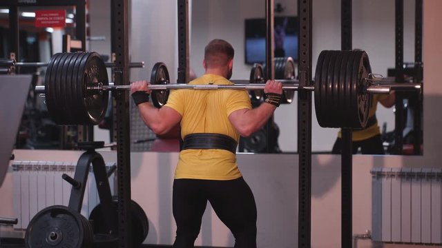 the man squats with a barbell 