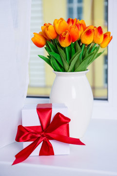 Close Up Of Beautiful Orange Tulips And Gift Box On A Window Sil