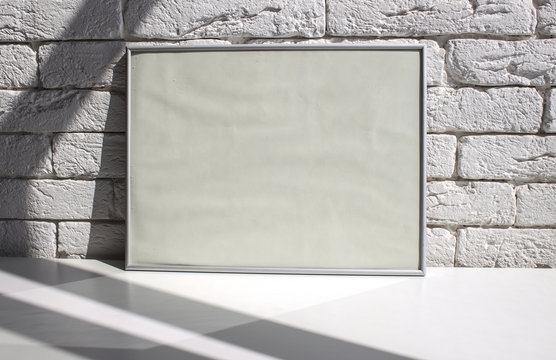 Aluminum frame on a white table against a white brick wall. Template.