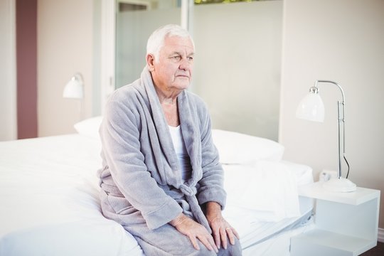 Thoughtful Senior Man Sitting On Bed