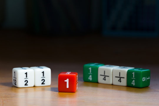 Fraction dices on wood table with dark background, selective focus on red dice