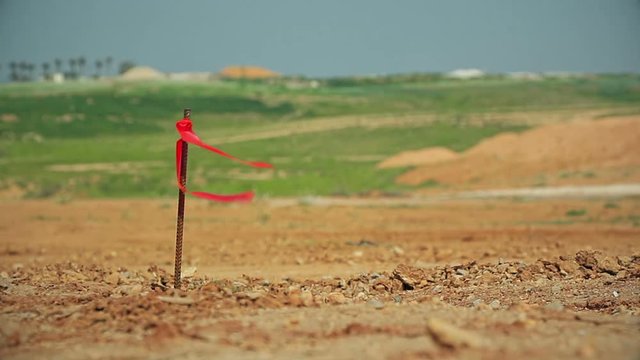 Metal survey peg with red flag on construction site.