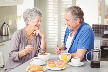 Fototapeta na wymiar Happy senior couple discussing while having breakfast