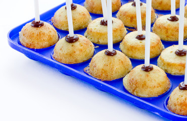 Baked cake pops with sticks in silicone mold on white background