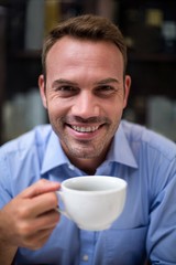 Close-up portrait of happy man holding coffee cup