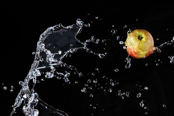 Fototapeta na wymiar Red apple apple flying in space with the water on a black background