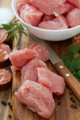 raw turkey owith black pepper on brown wooden board and chorizo