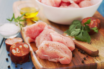 raw turkey with black pepper on brown wooden board and chourico