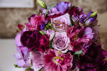 Rings on the beautiful wedding bouquet with roses on brown background
