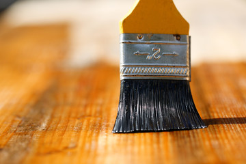 Paintbrush sliding over wooden surface, protecting wood