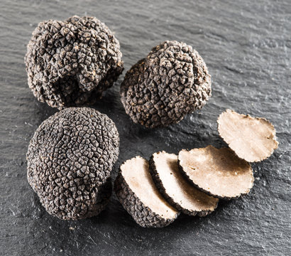 Black truffles and truffle slices on the graphite board.