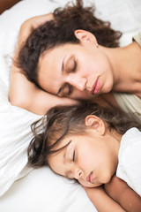 Fototapeta na wymiar Sleeping kid girl and her mother in the bed.