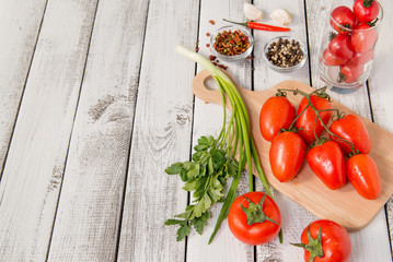 close up of fresh red delicious tomatoes with greenery on an old wooden background