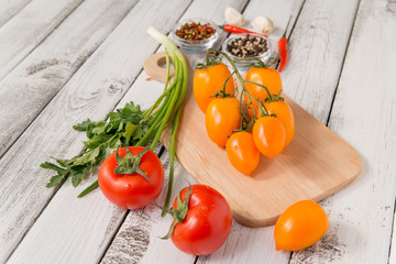 close up of fresh red and yellow delicious tomatoes with greenery on an old wooden background