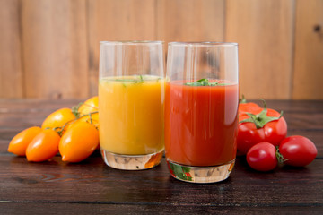 Glass of tomato juice with vegetables on old wooden background, with greenery and tomatoes