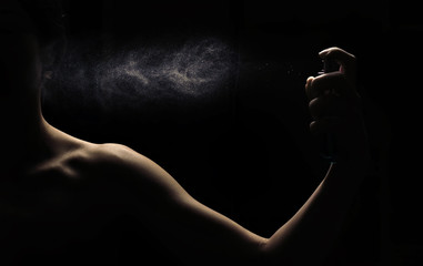 Woman's perfume in the hand on black background
