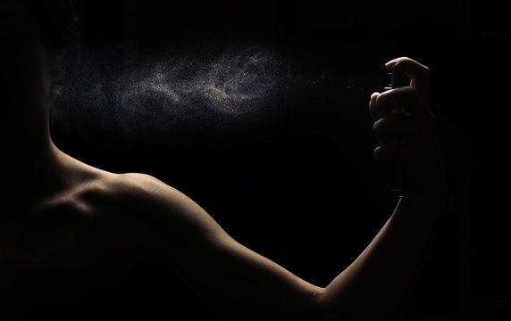 Woman's perfume in the hand on black background