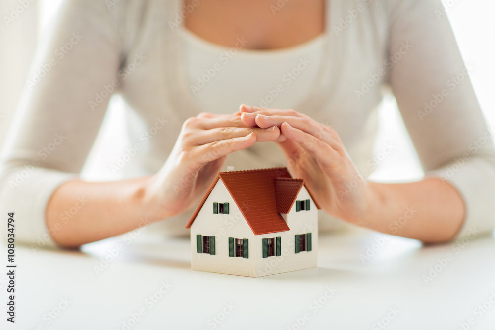 Poster close up of hands protecting house or home model