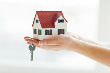 close up of hands holding house model and keys