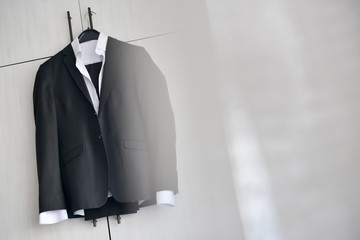 Black suit hanged to a wood closet in natural light