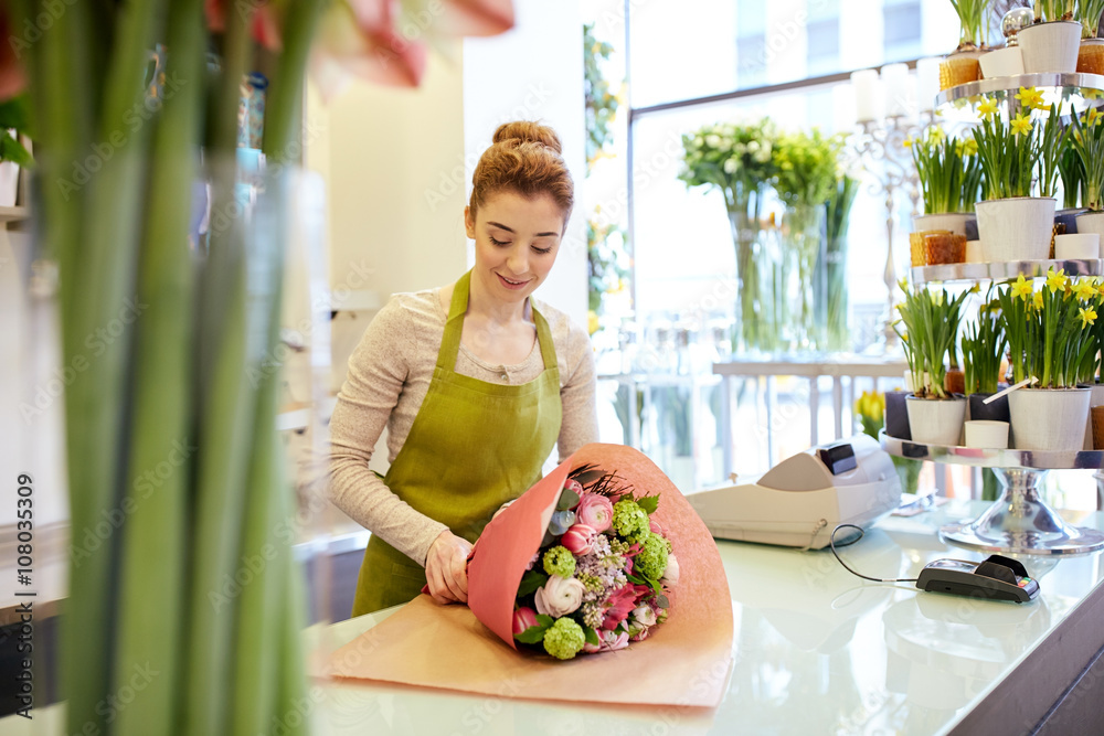 Wall mural smiling florist woman packing bunch at flower shop