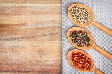 Spices and sea salt in spoons on wooden background