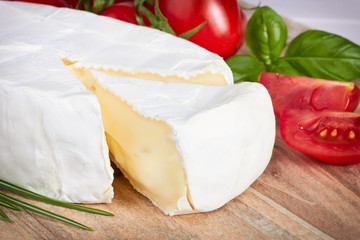 Goat cheese, cherry tomato, and herbs on a wooden board