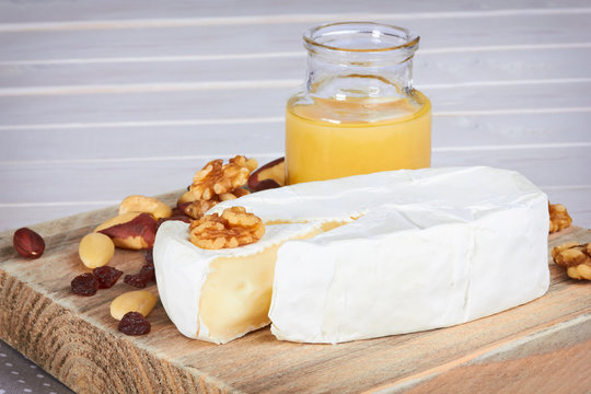 cheese with nuts on wooden tray and white table