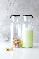 fresh homemade pistachio milk in a transparent bottle and pistac
