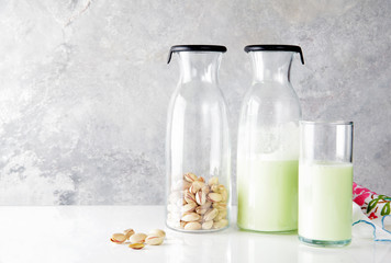 fresh homemade pistachio milk in a transparent bottle and pistac