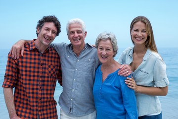 Cheerful family by sea against blue sky