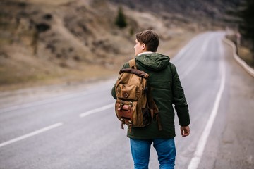 a man with a backpack walks alone upon the road