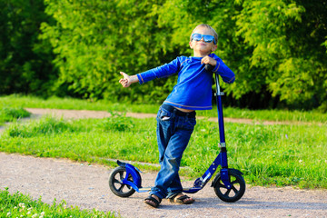 happy little boy enjoy riding scooter in summer