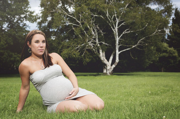 Naklejka na ściany i meble Beautiful pregnant woman on the grass