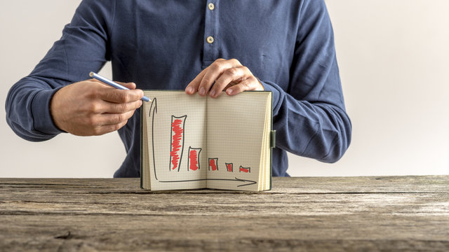 Businessman showing his notebook with falling financial graphs