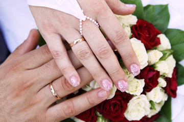 Obraz na płótnie Canvas Hands with wedding rings and bridal bouquet