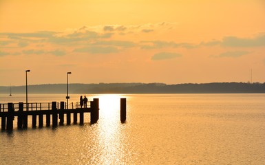 Obraz premium Sonnenuntergang am Wasser - Seebrücke in Glücksburg