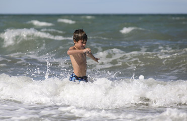 Fototapeta premium Niño Jugando entre las Olas del Mar