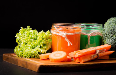 Fresh green and carrot smoothie in the glass on black stone. Lifestyle concept