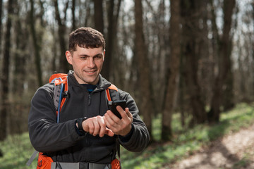 Man hiker taking photo with smart phone in forest