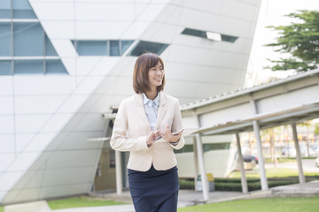 Attractive asian business woman working on tablet computer outsi