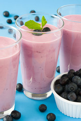 Blueberry smoothie in a glass on a blue background
