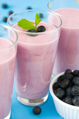 Blueberry smoothie in a glass on a blue background
